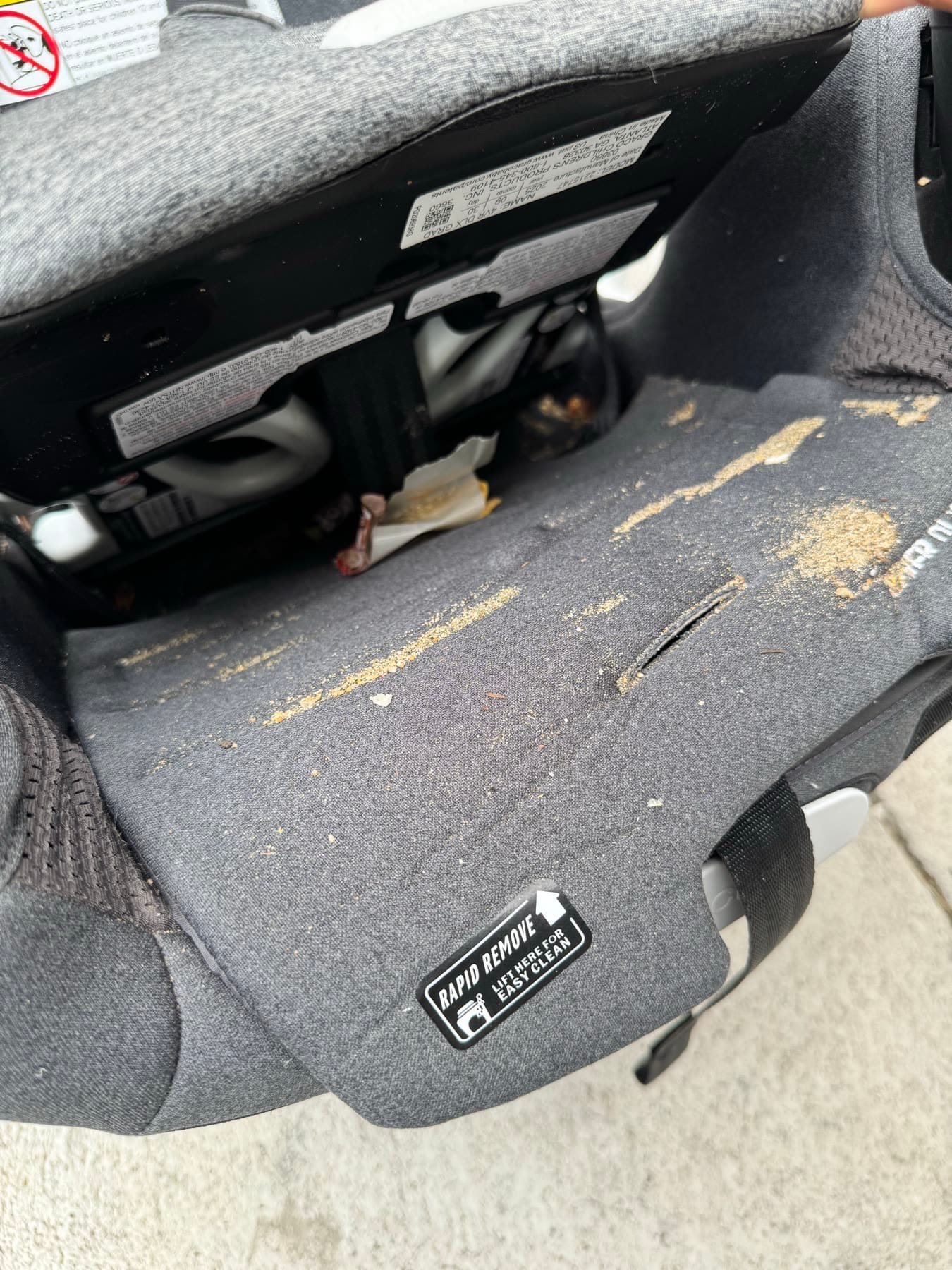The seat pad lifted to show ground-in crumbs and sand on the fabric underneath
