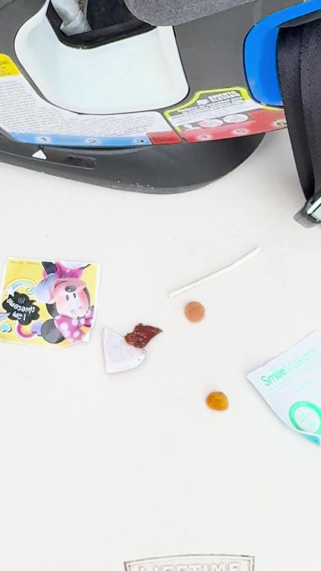 What came out of one car seat, laid on the table: a Minnie Mouse sticker, a raisin, a piece of cracker, a straw and a wrapper